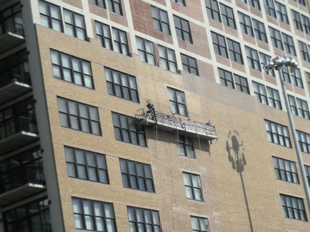 Professional window cleaner working on high-rise commercial building in London