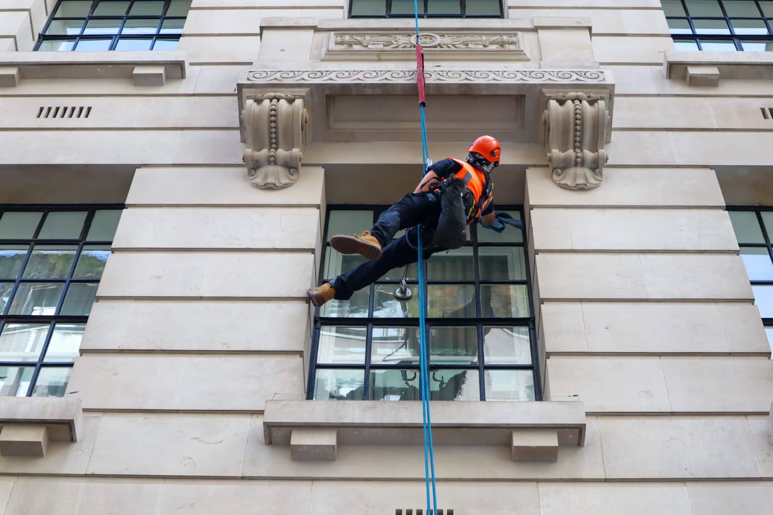 Professional window cleaner working on high-rise commercial building in London